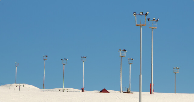 A floodlight installation in the mountains with snow-covered ski slope.